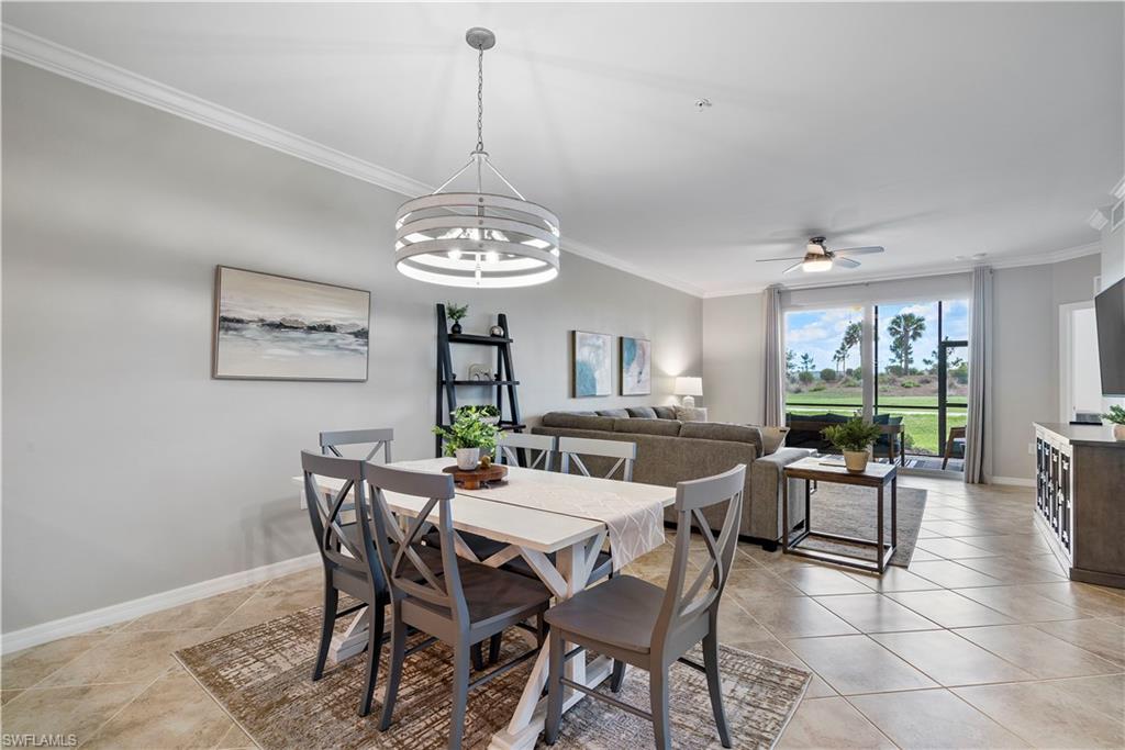 Dining room with crown molding, ceiling fan, a chandelier, and light tile patterned flooring