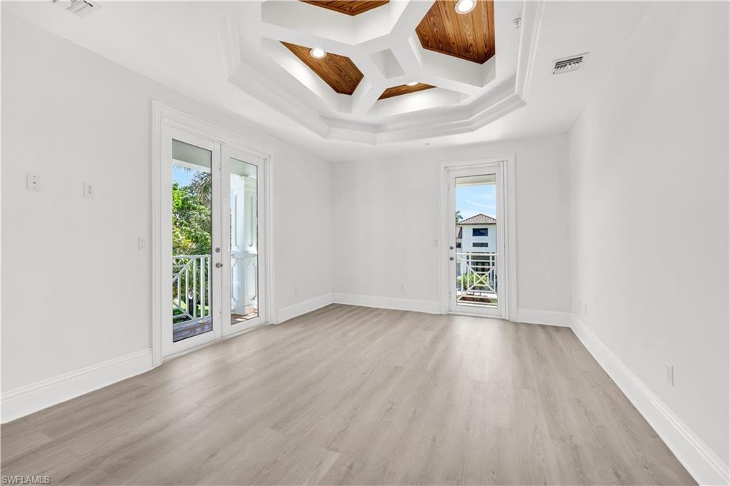 Front guest-suite featuring private balconies, coffered ceiling, light wood finished floors, and beam ceiling