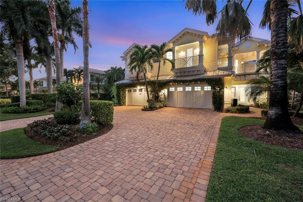 Front view of the home at dusk featuring the paved driveway, second floor balcony and 2-car garage