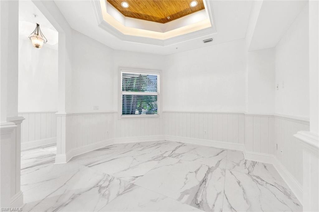 Front sitting room with a tray ceiling, light marble finish floors, recessed lighting, wainscoting, and wooden ceiling