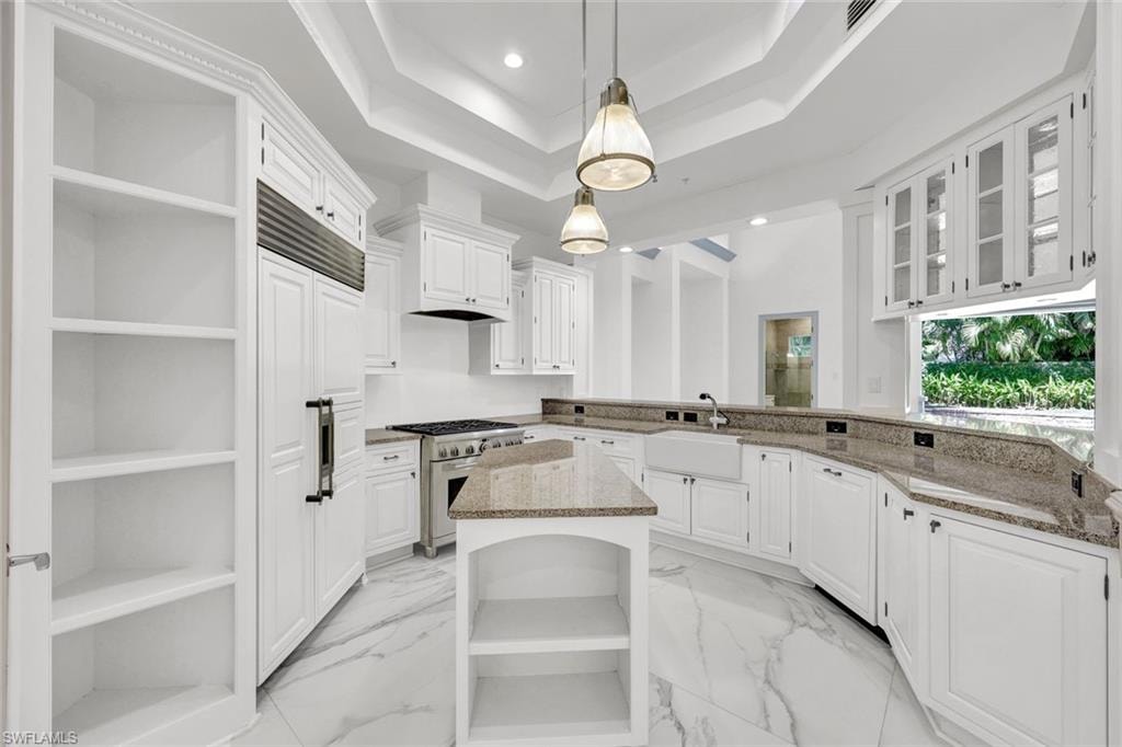 Kitchen featuring open shelves, white cabinets, a kitchen island, light stone counters, and pendant lighting, sub-zero refrigerator