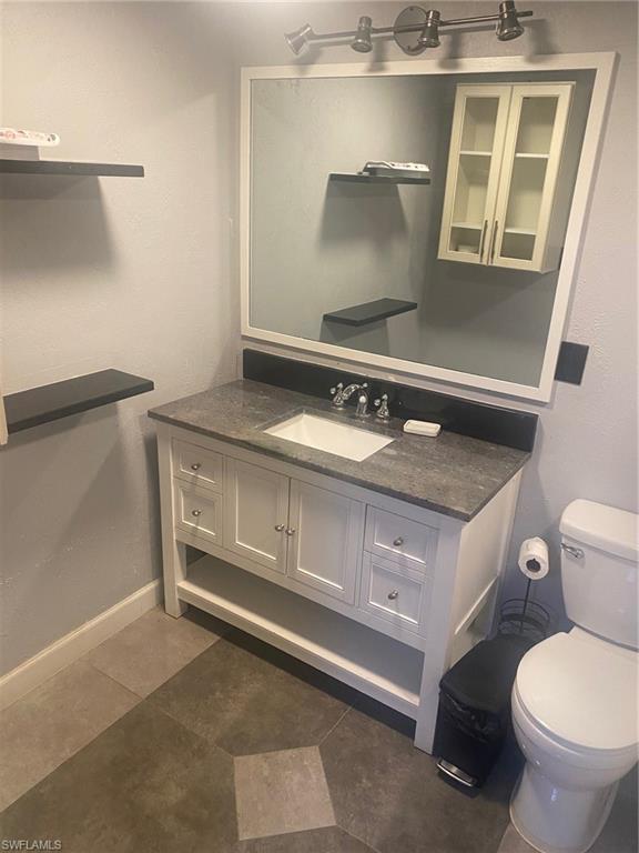 Half bathroom with vanity, a textured wall, and dark tile patterned floors