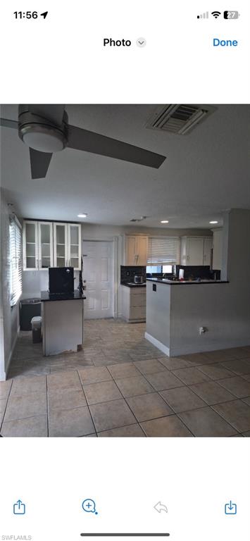 Kitchen featuring dark countertops, a peninsula, light tile patterned floors, and white cabinets