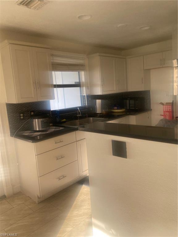 Kitchen with white cabinetry, tasteful backsplash, and light tile patterned floors