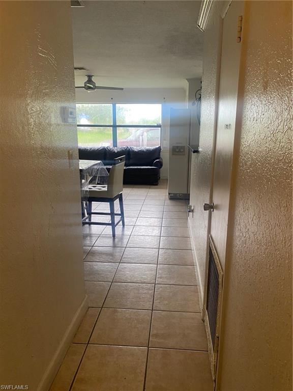 Corridor featuring a textured wall and light tile patterned flooring