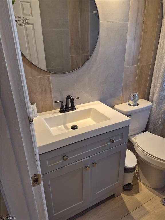 Full bath with tile walls, a shower with curtain, and vanity