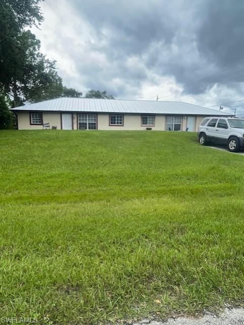 Ranch-style home featuring stucco & siding, a metal roof 2023, front lawn