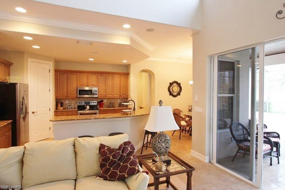 Kitchen with light stone countertops, appliances with stainless steel finishes, recessed lighting, crown molding, and open floor plan