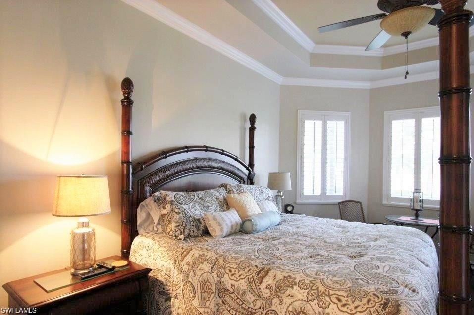 Bedroom featuring a tray ceiling, crown molding, and ceiling fan