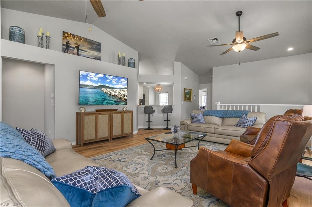 Living area with ceiling fan, wood finished floors, and high vaulted ceiling