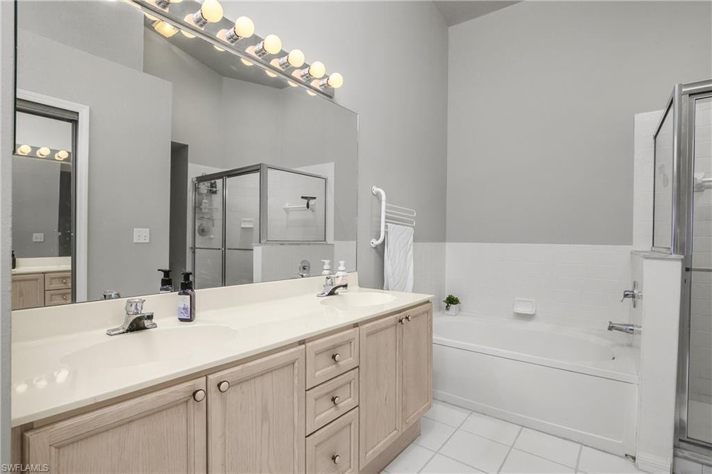 Full bathroom with double vanity, a garden tub, light tile patterned floors, and a shower stall