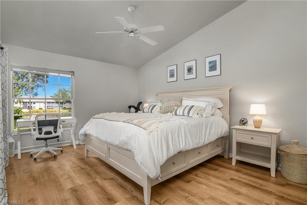 Bedroom with lofted ceiling, light wood-style floors, ceiling fan, and a desk