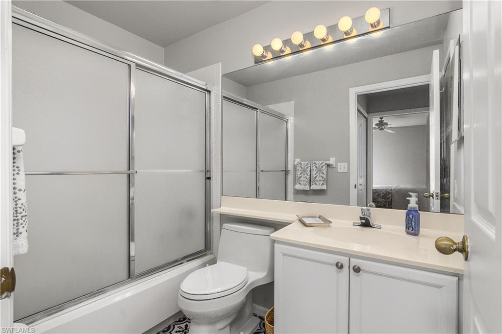Full bath featuring bath / shower combo with glass door, vanity, and ceiling fan