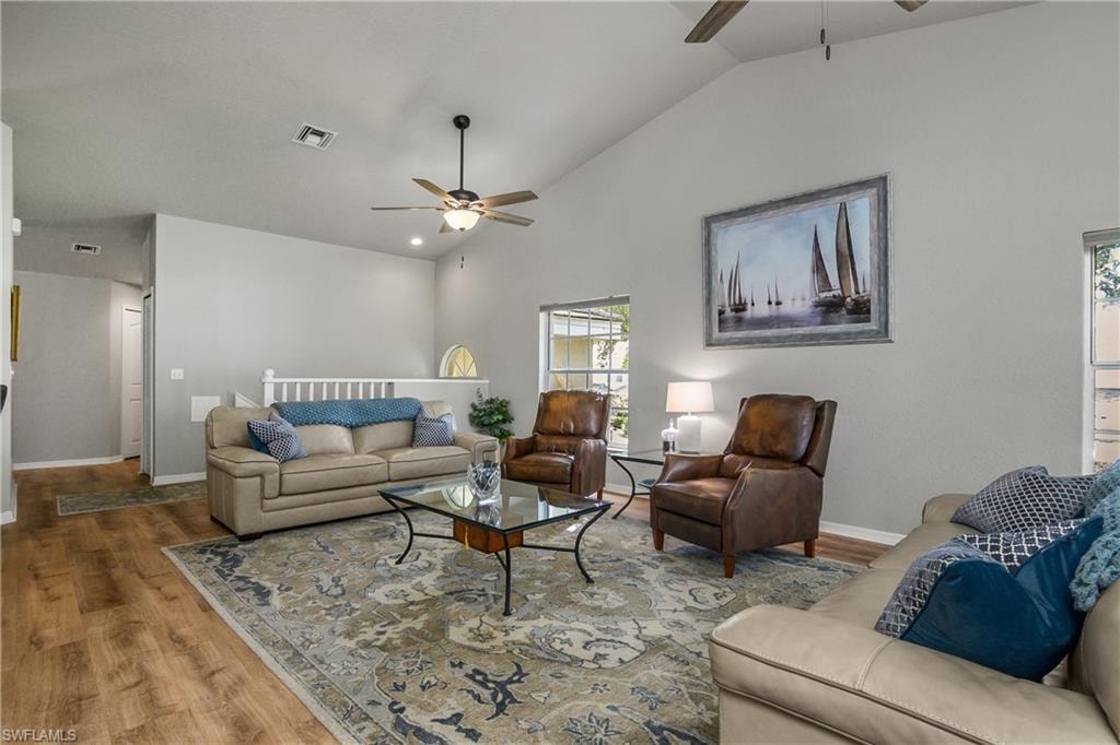 Living room with wood finished floors, ceiling fan, and high vaulted ceiling