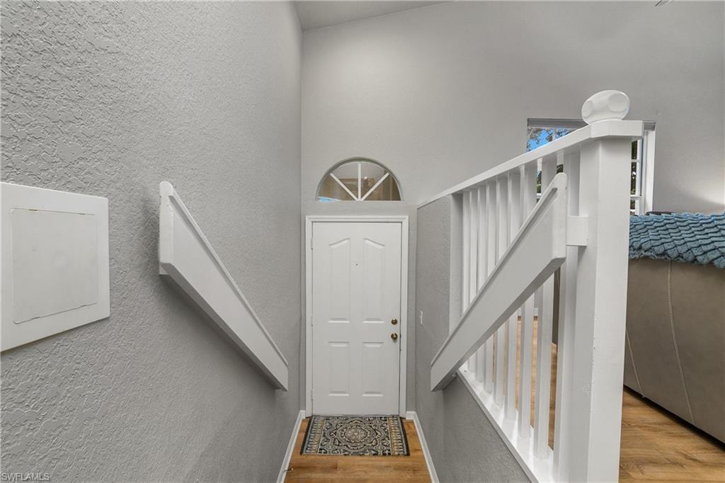 Stairway featuring a textured wall, a towering ceiling, and wood finished floors
