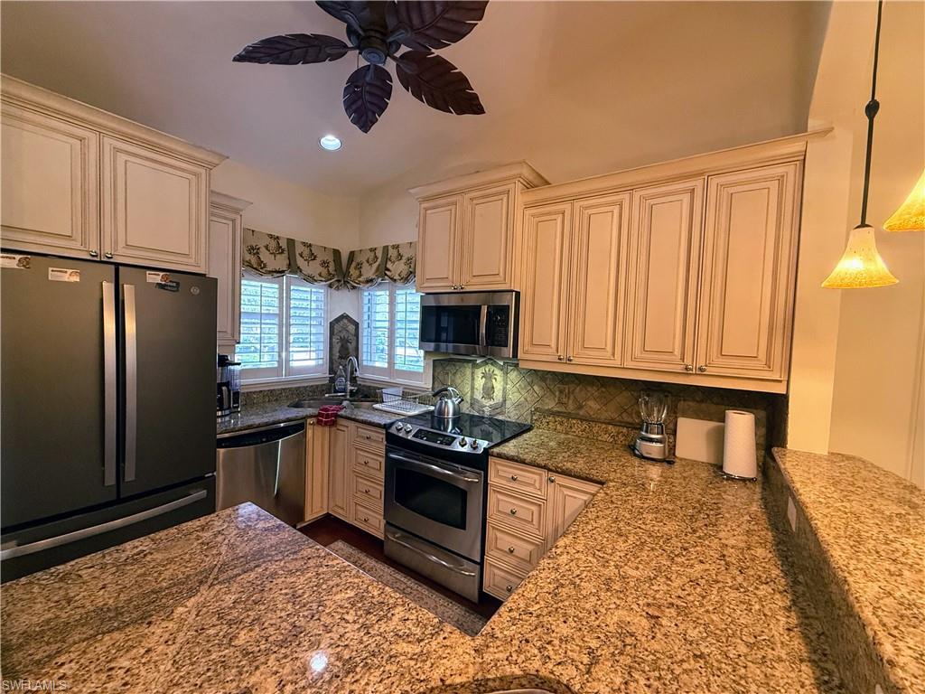 Kitchen with stainless steel appliances, dark stone counters, recessed lighting, backsplash, and cream cabinets