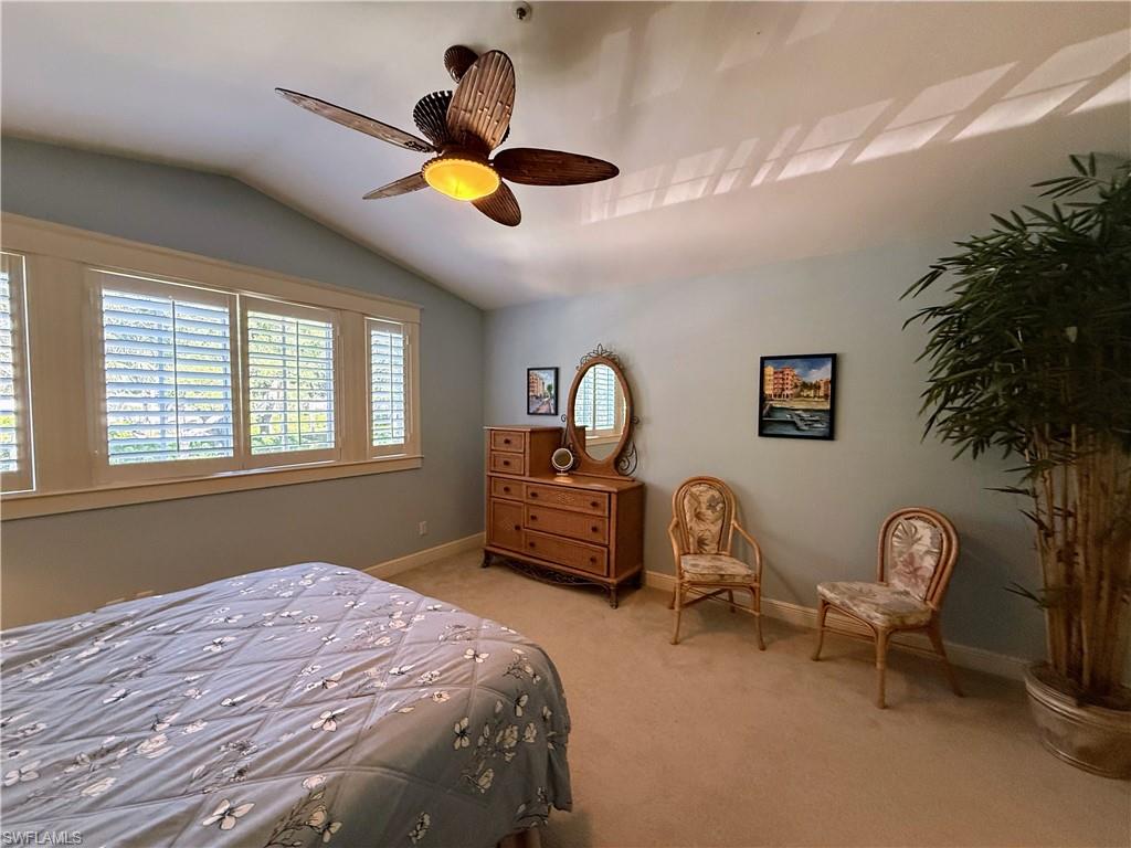 Bedroom with lofted ceiling, light carpet, and a ceiling fan