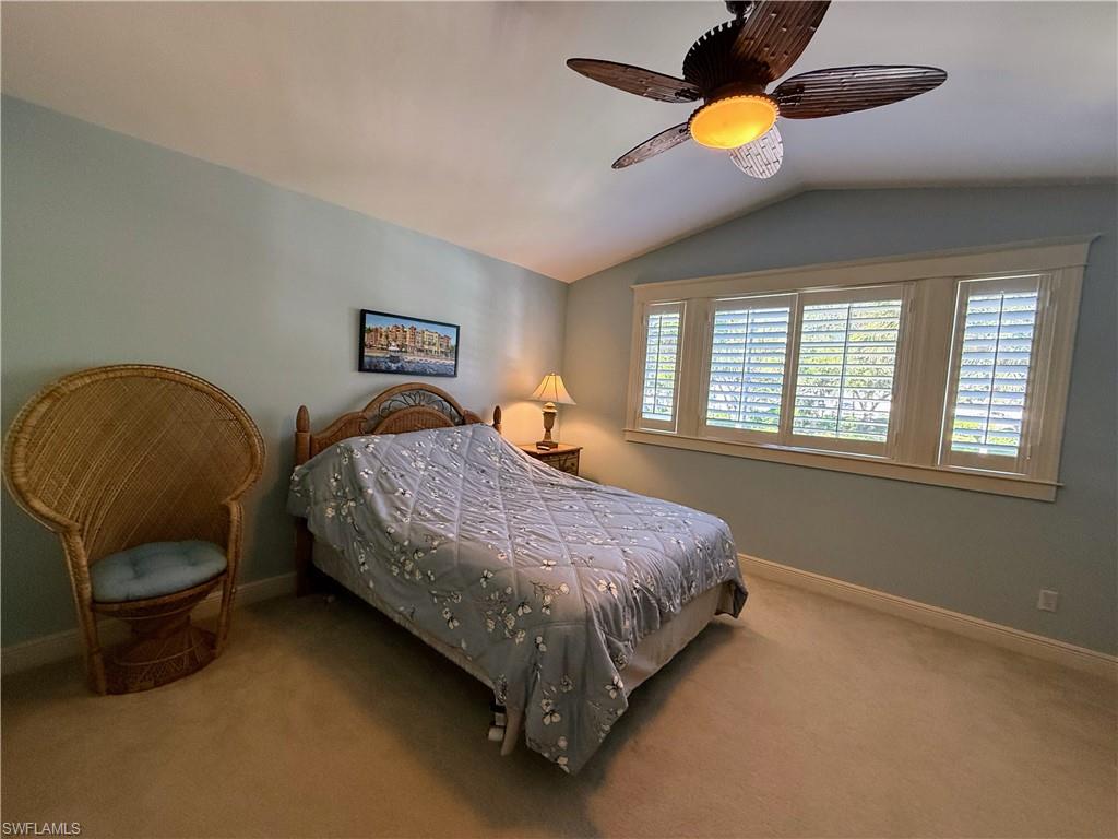Carpeted bedroom with vaulted ceiling and a ceiling fan
