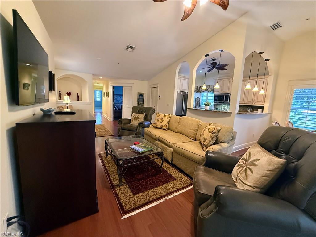 Living room featuring dark wood finished floors, lofted ceiling, a ceiling fan, and healthy amount of natural light