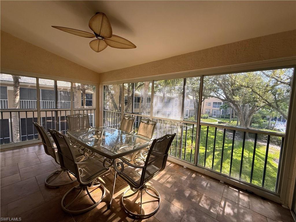 Sunroom featuring vaulted ceiling, healthy amount of natural light, and a textured wall
