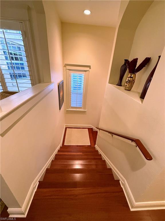 Stairway featuring healthy amount of natural light, wood finished floors, and recessed lighting