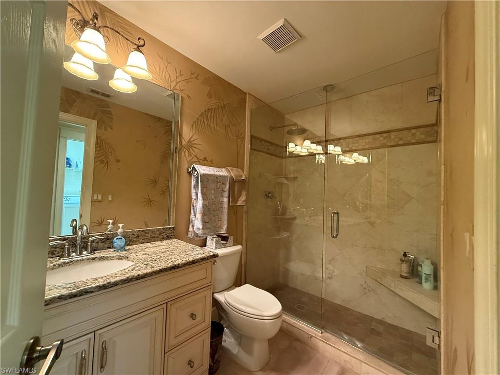 Full bath with vanity, a shower stall, a chandelier, and wallpapered walls