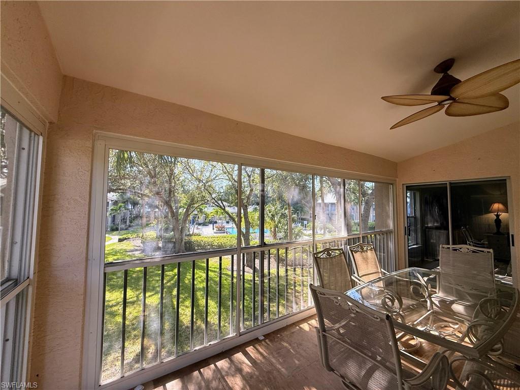 Sunroom / solarium with vaulted ceiling, a textured wall, and wood finished floors