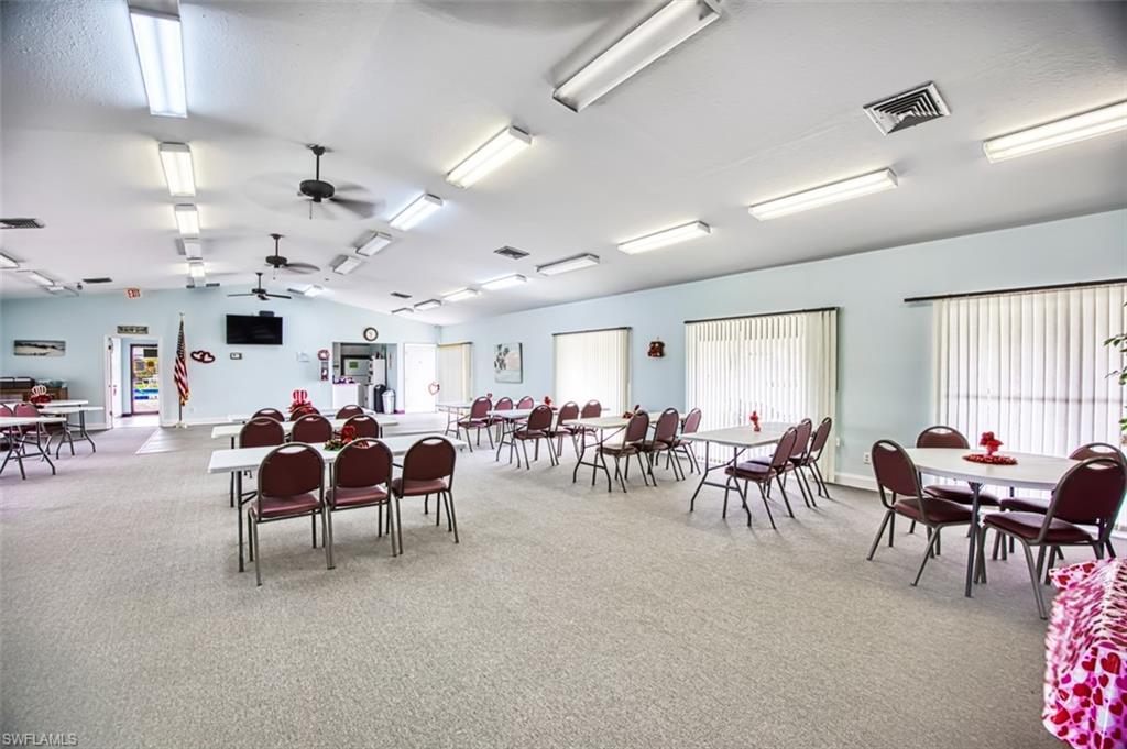Dining area featuring light carpet, vaulted ceiling, and a ceiling fan