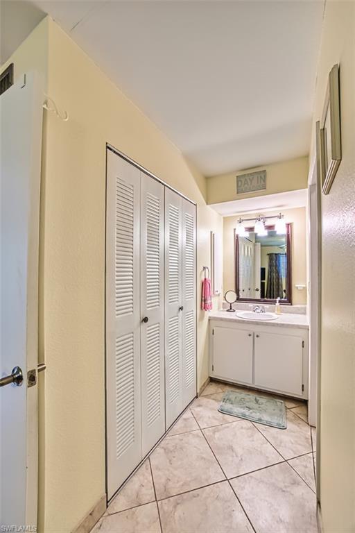 Bathroom featuring vanity, light tile patterned flooring, and a closet