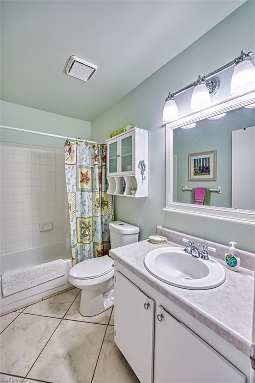 Bathroom with vanity, shower / bathtub combination with curtain, and light tile patterned floors