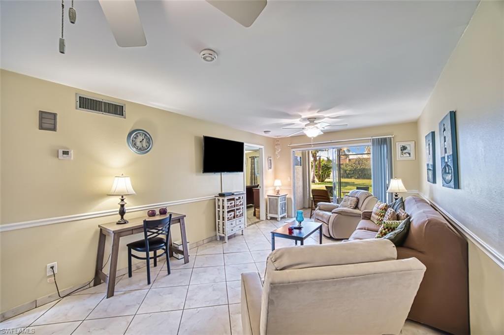 Living room with light tile patterned floors and a ceiling fan