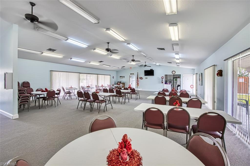 Dining area featuring light colored carpet, vaulted ceiling, plenty of natural light, and ceiling fan