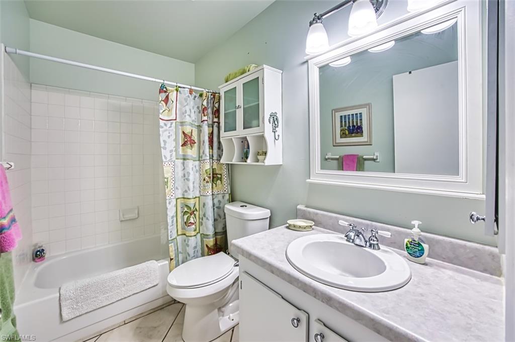 Bathroom featuring shower / bathtub combination with curtain, vanity, and light tile patterned floors