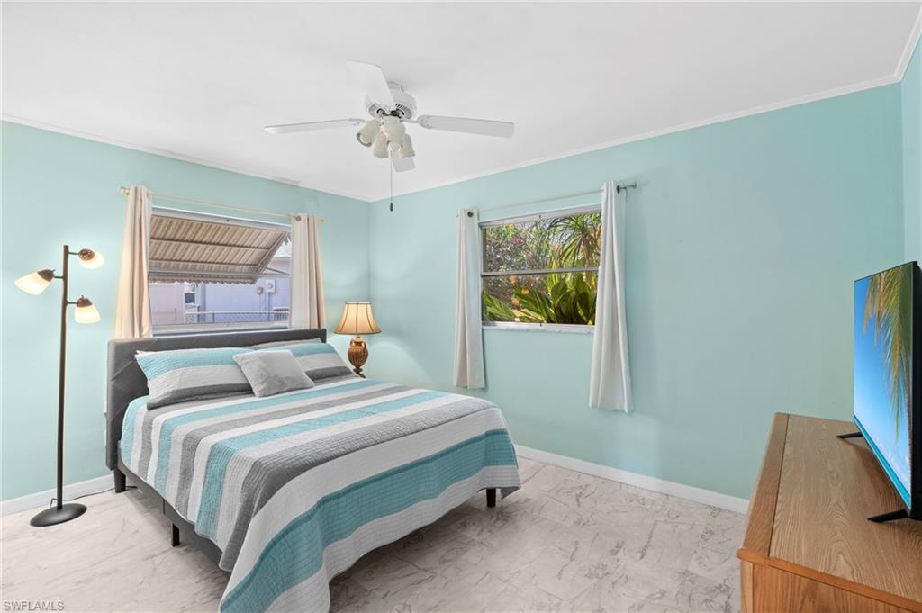 Bedroom featuring light marble finish flooring, ceiling fan, and multiple windows