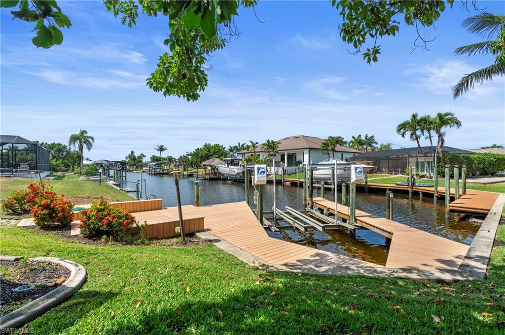Dock with boat lift, a yard, a water view, and a residential view