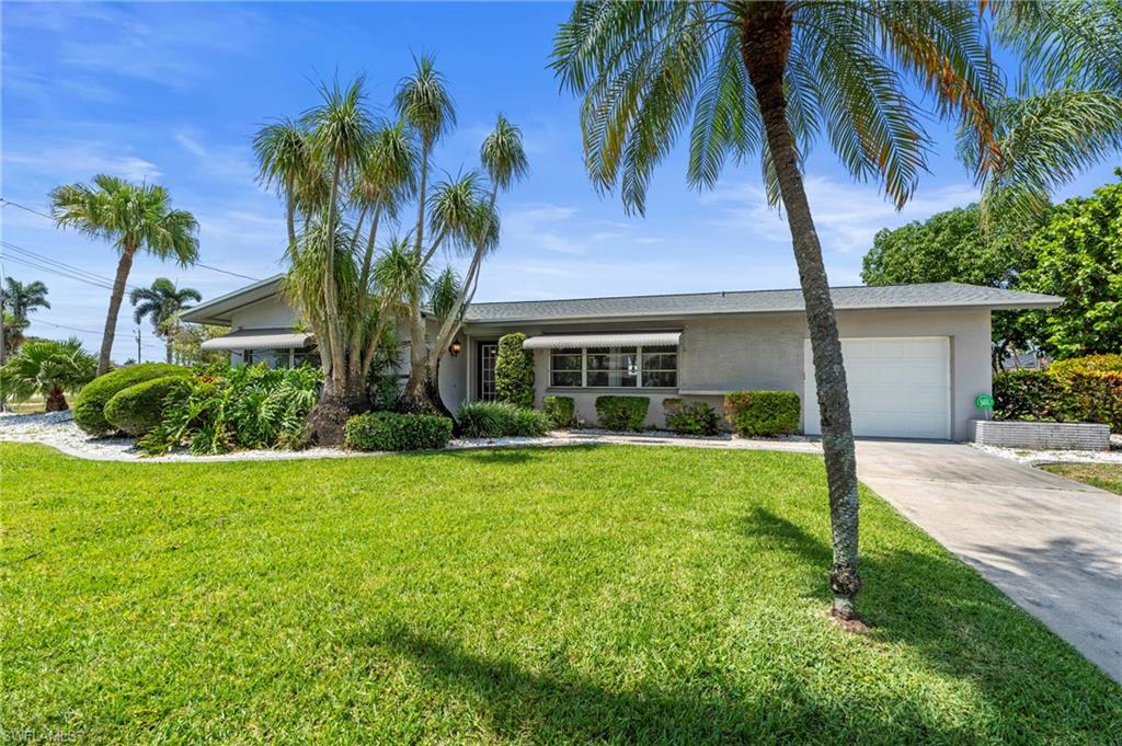 View of front of home featuring stucco siding, driveway, a garage, and a front lawn