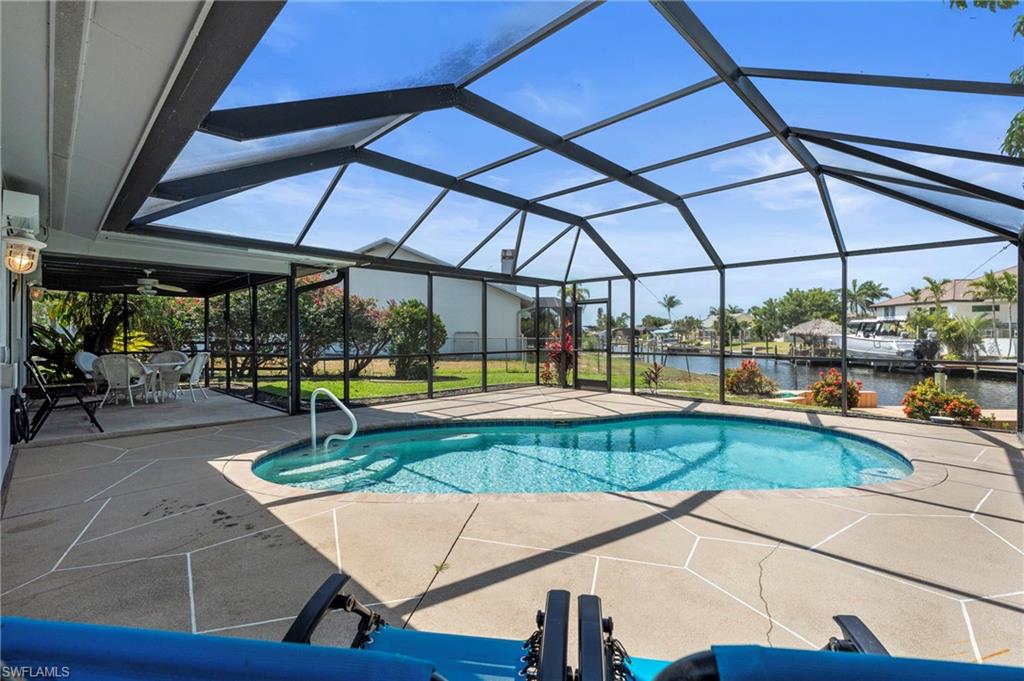 Dock with glass enclosure, a yard, an outdoor pool, a water view, and boat lift