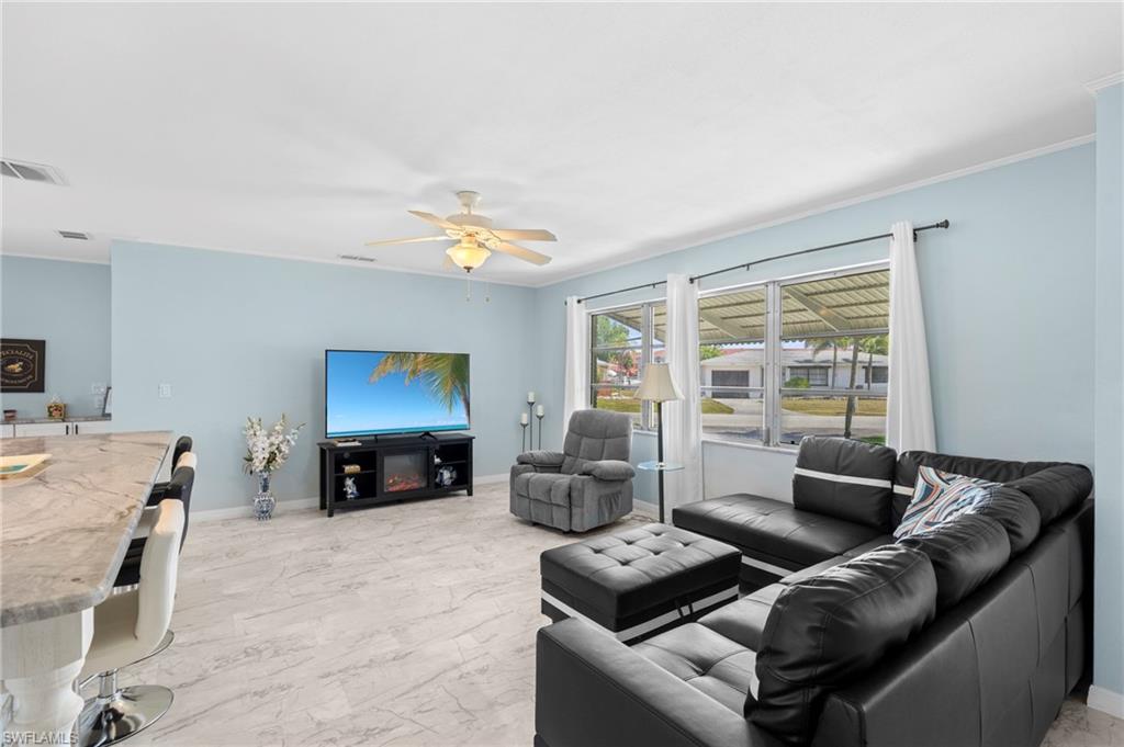 Living area with light marble finish floors, crown molding, and ceiling fan