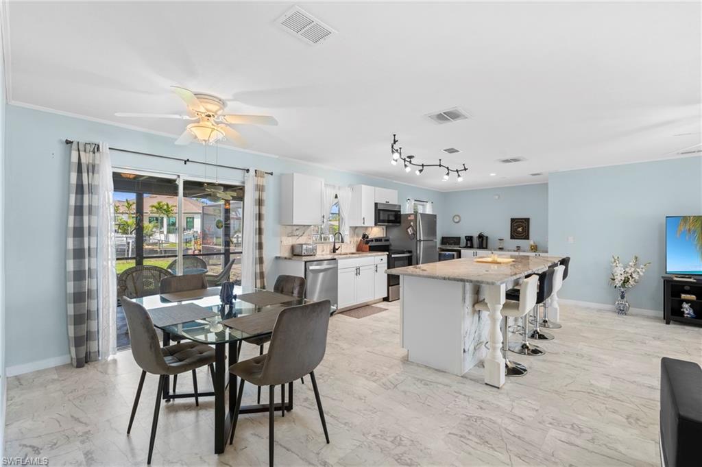 Dining area featuring ceiling fan, light marble finish flooring, and crown molding