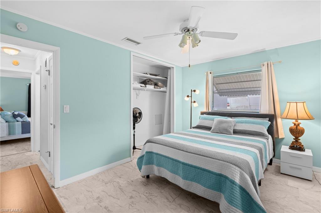 Bedroom featuring marble look tile flooring, ceiling fan, a closet, and ornamental molding