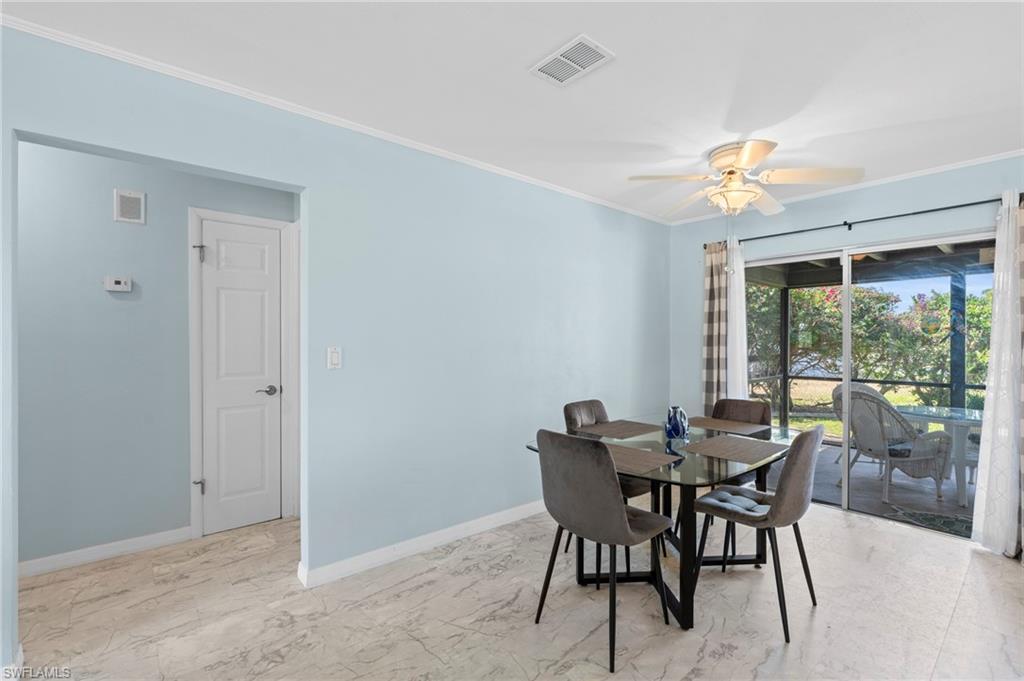 Dining area featuring light marble finish flooring, ornamental molding, and ceiling fan