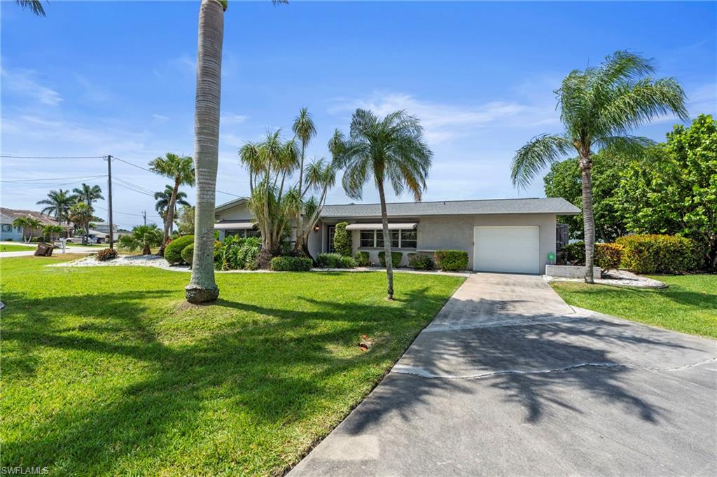 Ranch-style house featuring driveway, a garage, a front yard, and stucco siding