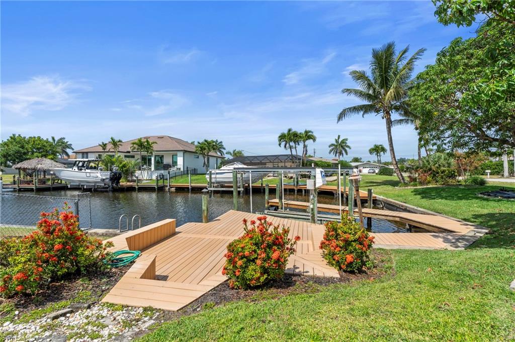 Dock with boat lift, a water view, and a lawn