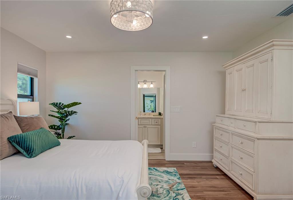 Bedroom with light wood finished floors, recessed lighting, and ensuite bathroom