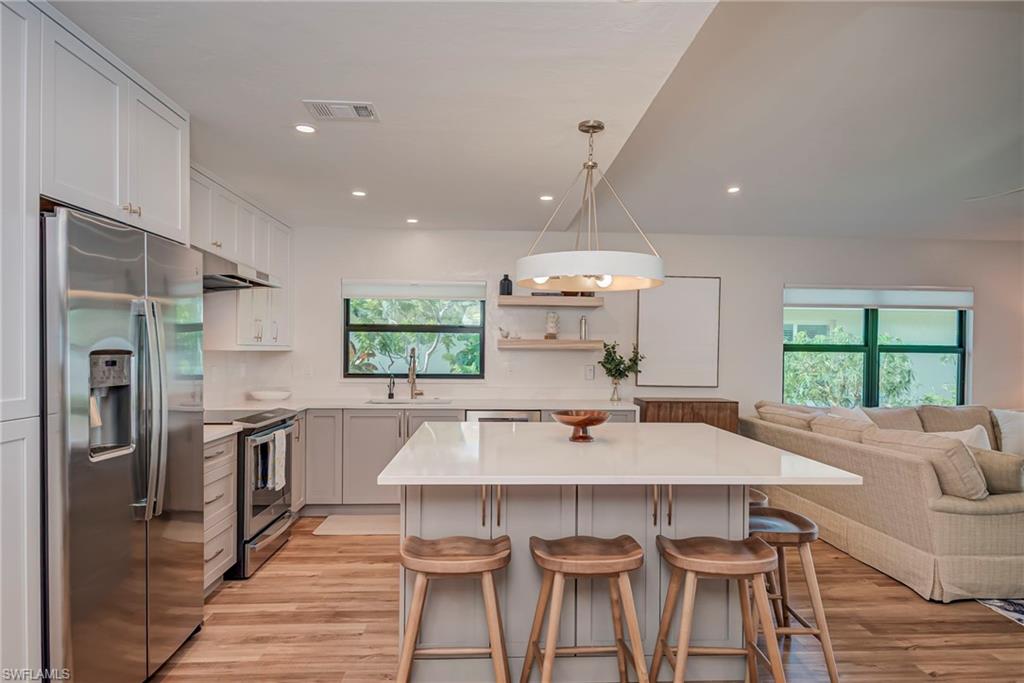 Kitchen with stainless steel appliances, a center island, hanging light fixtures, a breakfast bar, and open floor plan