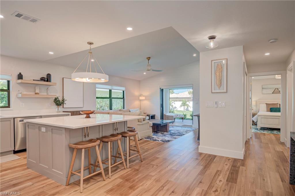 Kitchen with gray cabinetry, a kitchen breakfast bar, hanging light fixtures, light wood finished floors, and recessed lighting