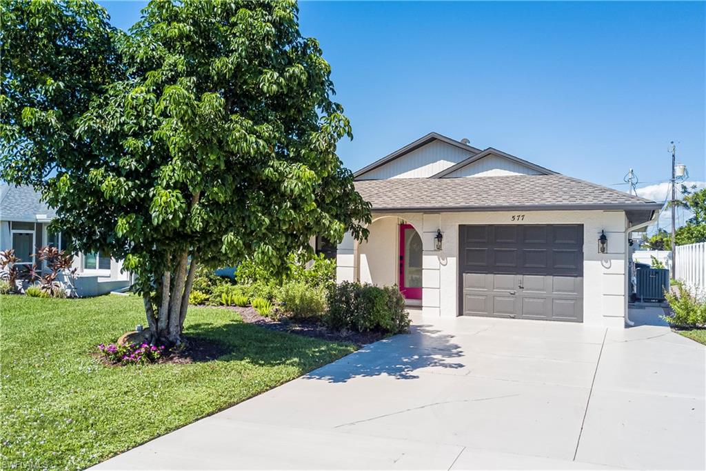 View of front of property featuring a shingled roof, driveway, a garage, and a front yard