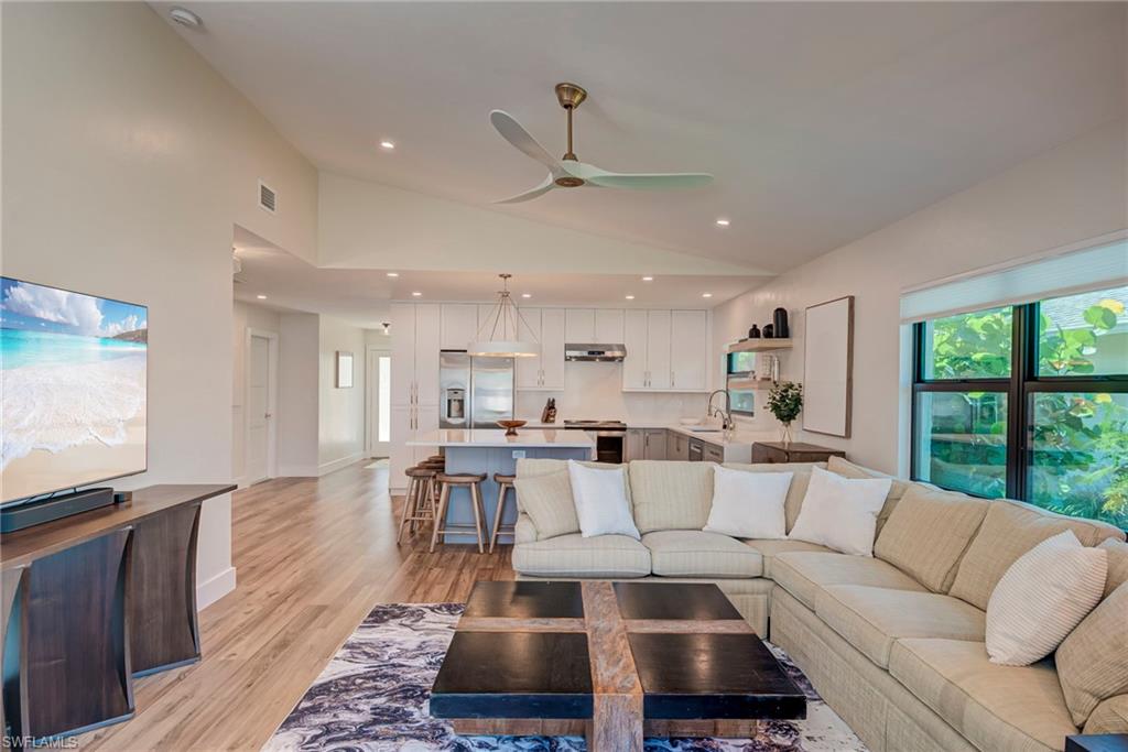 Living room with light wood-style flooring, recessed lighting, ceiling fan, and high vaulted ceiling