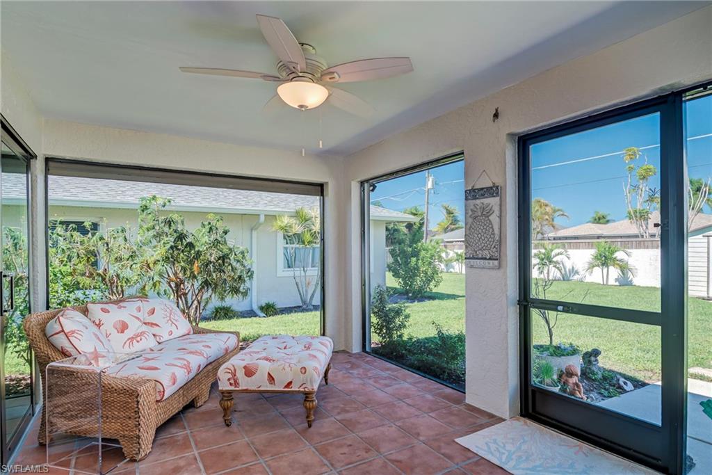 Sunroom / solarium featuring a ceiling fan, tile patterned floors, and a textured wall