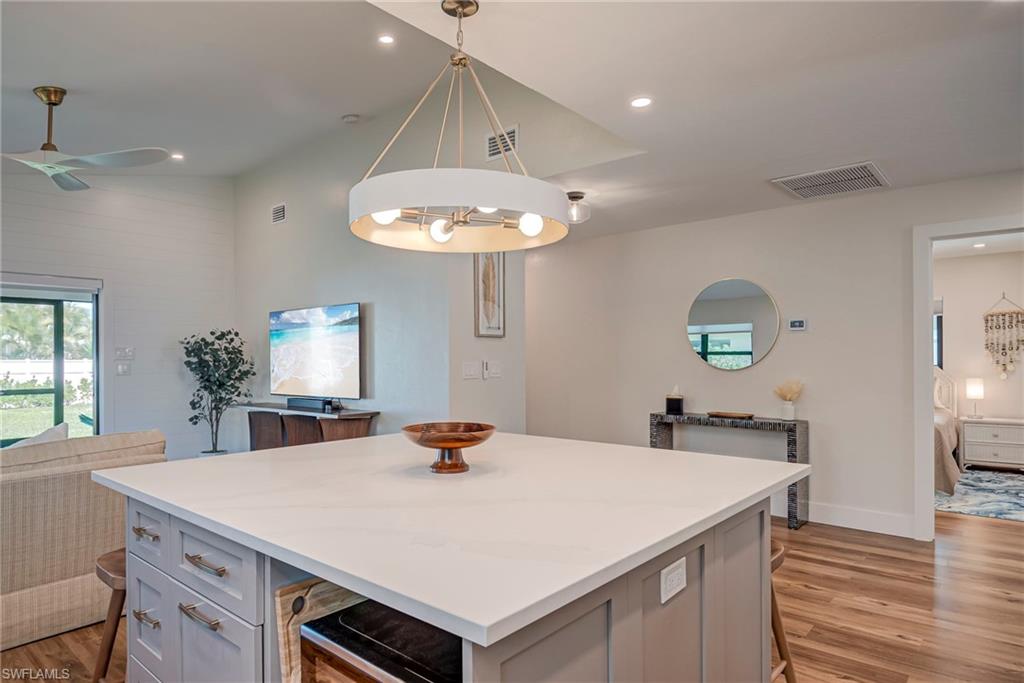 Kitchen with light wood-style flooring, a kitchen island, gray cabinets, a chandelier, and recessed lighting